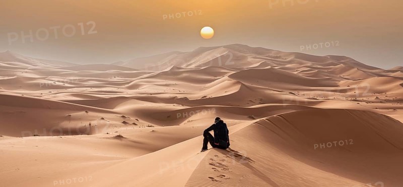 A person sitting in the Erg Chebbi desert in the African Sahara, Morocco, Africa