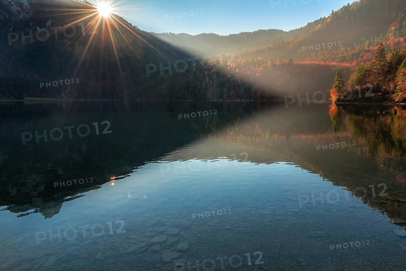 Contemplative autumn landscape with wooded hills, autumn forest, and the Alpsee lake, on a sunny morning, near Fussen, in Bavaria, Germany, Europe