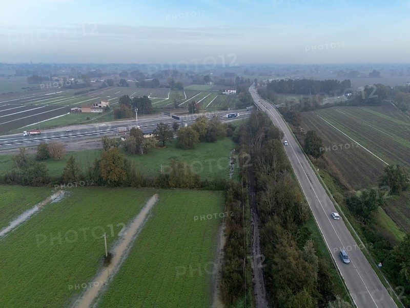 Aerial view of a highway crossing the italian countryside after heavy rain, with flooded fields and a rest area visible