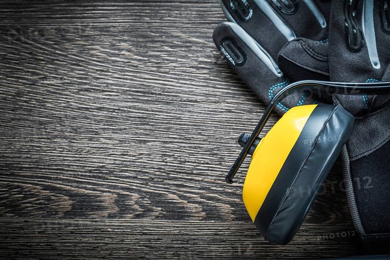 Safety gloves earmuffs on wooden board