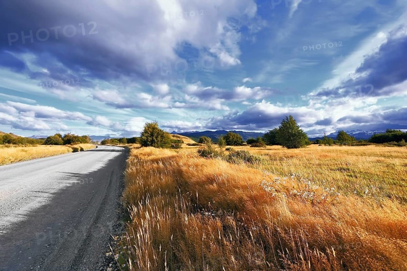 The beginning of autumn in the southern Patagonia. Amazingly beautiful sunset illuminates the distant mountains and the dirt road with bright light