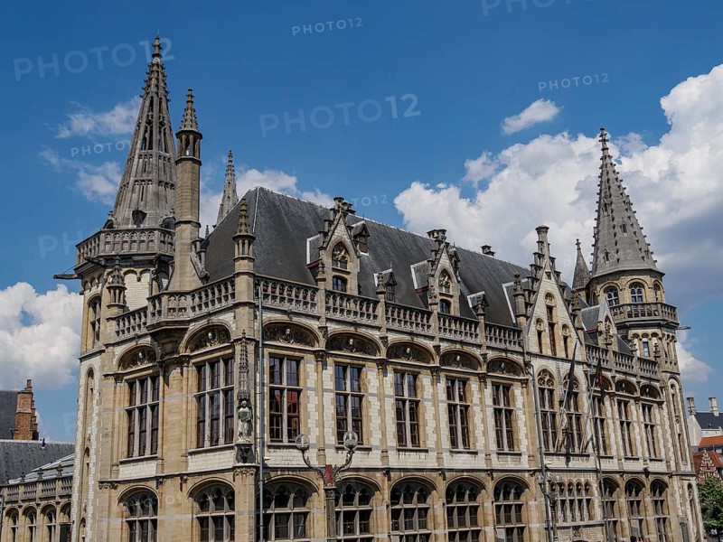 Majestic building with pewter towers and detailed decorations on a clear blue sky, Ghent, Belgium, Europe