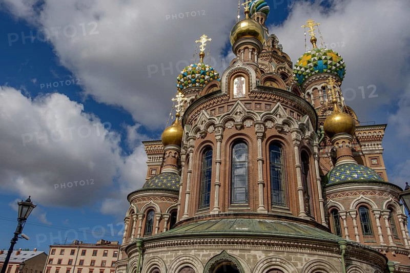 Russian church with magnificent onion domes and richly decorated façades in the sunlight against a white-blue sky