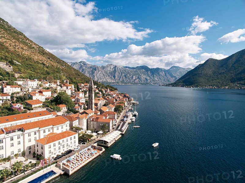 Swimming pool and private beach on the shore of the Bay of Kotor overlooking ancient houses. Perast, Montenegro. Drone.