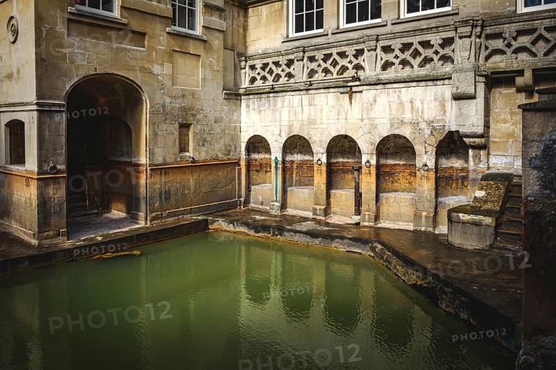 Water and buildings in an old roman bath in the city of Bath in the united kingdom england