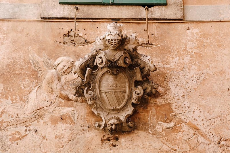 A bas-relief on the facade of a building in the old town of Kotor in Montenegro. Knight's shield and armor, dove and angels.