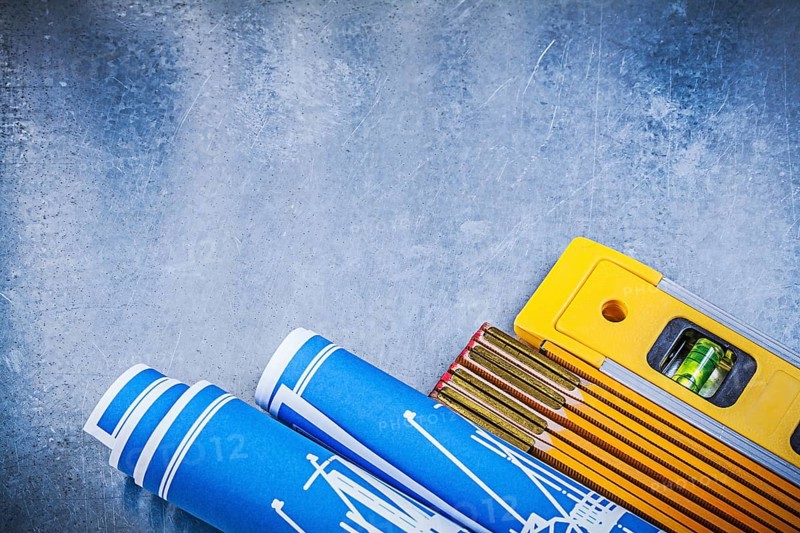 Wooden meter blue rolled construction drawings level on metallic background