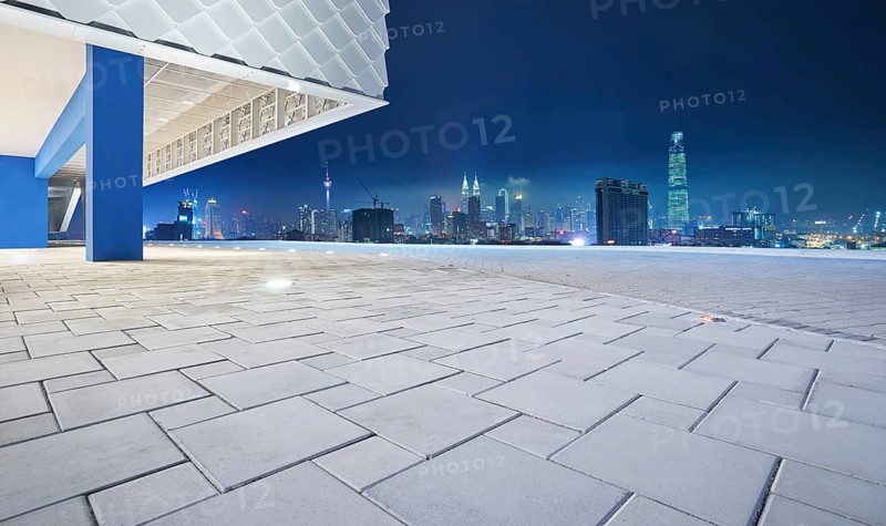 Perspective view of empty floor with modern building exterior and cityscape skyline . Night scene