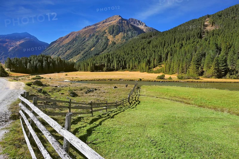 Rural idyll. Headwaters National Park Krimml waterfalls. Farm fields separated from the dirt road the low fence made ??of logs