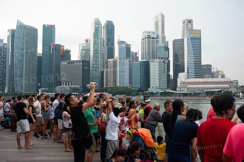 04.08.2018, Singapore, Republic of Singapore, Asia, Visitors watch a flight manoeuvre by the local air force over Marina Bay against the imposing backdrop of the business district in preparation for the annual National Day celebrations, Asia