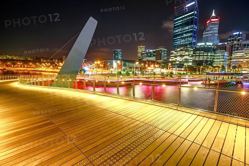 Wooden walkway of Elizabeth Quay pedestrian bridge illuminated by night at Elizabeth Quay marina, a new tourist attraction in Perth, Western Australia. Esplanade on background. Night scene, Perth, Australia, Oceania