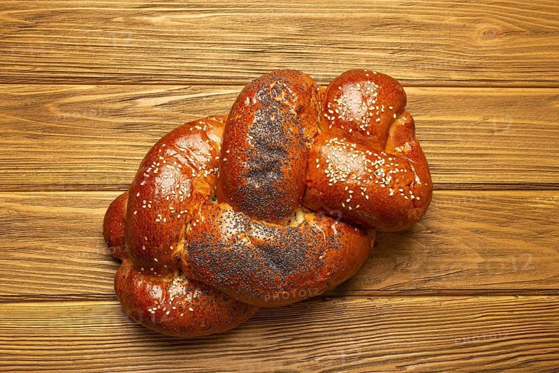 Freshly baked Challah bread covered with poppy and sesame seeds, top view on rustic wooden background, traditional festive Jewish cuisine, food photography, food photography
