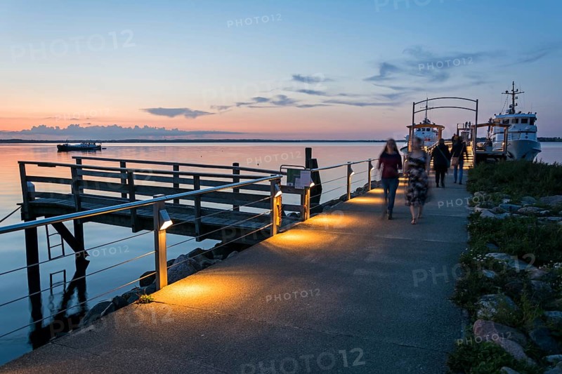 Boardwalk and ferry at the calm Baltic Sea in scenic evening light