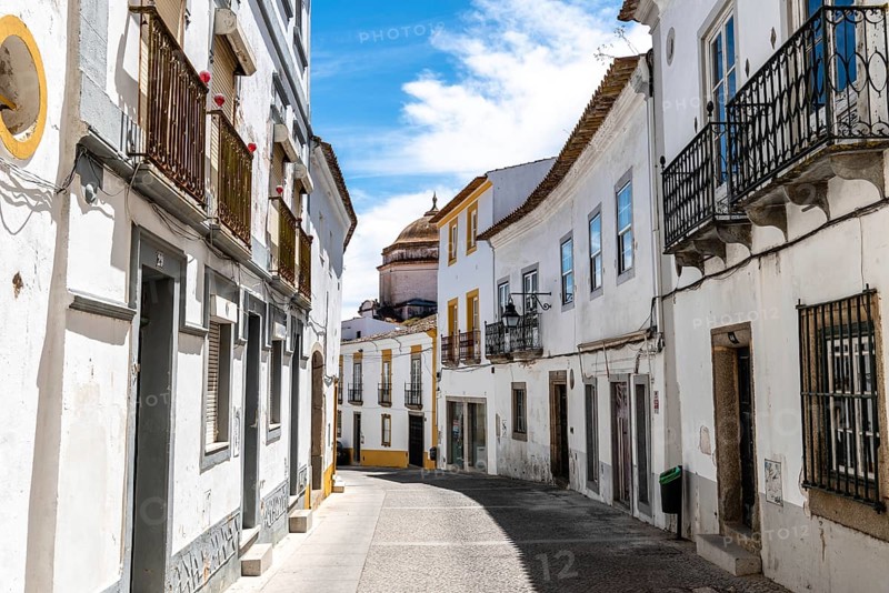 Evora, Portugal, June 30, 2022: Street in the old town with typical whitewashed houses with balconies. Alentejo, Portugal, Europe