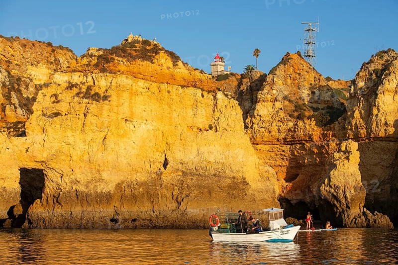 Stand-up paddler and fishing boat at Ponta de Piedade, Lagos, Algarve, Portugal, Europe
