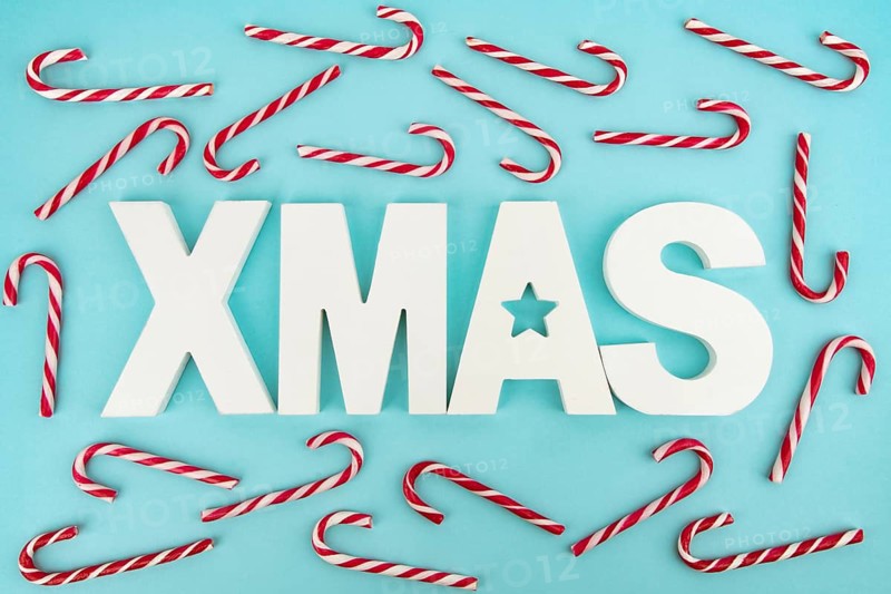 Zuckerstangen und hölzerne XMAS-Buchstaben auf blauem, hellem Hintergrund