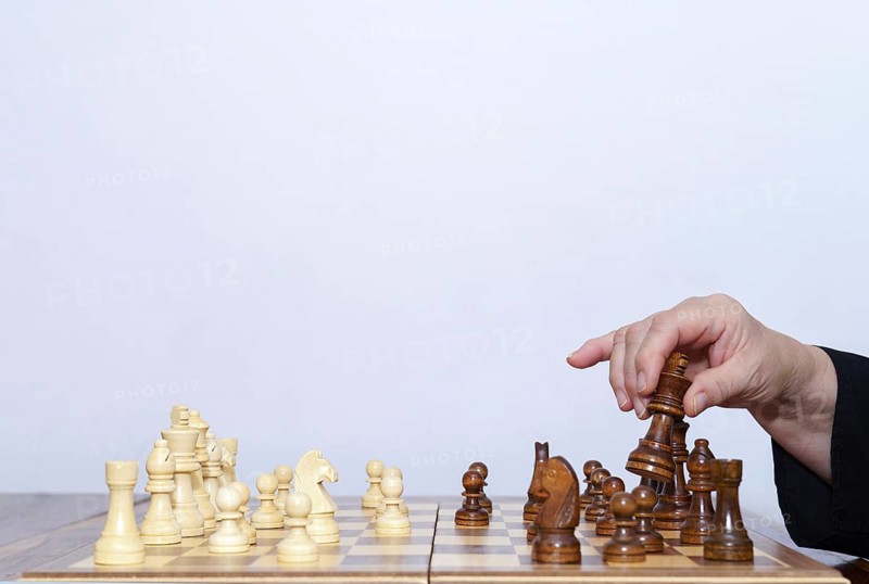 Close-up of a woman's hands playing chess with a white background and copy space