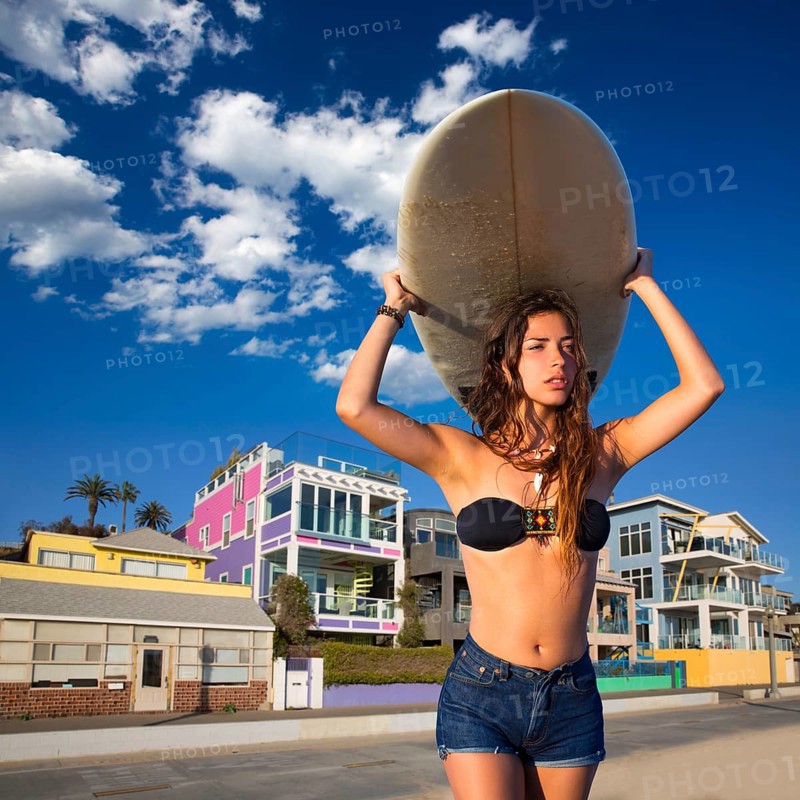 Brunette surfer teen girl holding surfboard in Santa Monica beach California