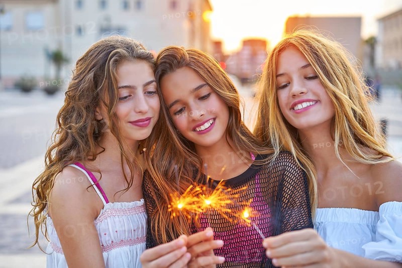 Best friends teen girls with sparklers at sunset in the city