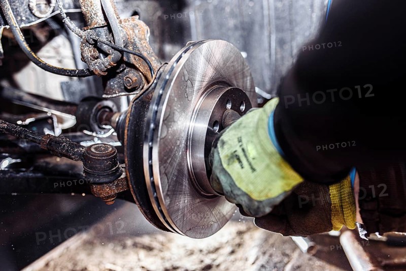 Mechanic adjusting a brake system part, focused on hands in a workshop