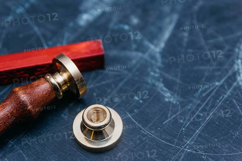 Brass seal with red wax on a textured dark background