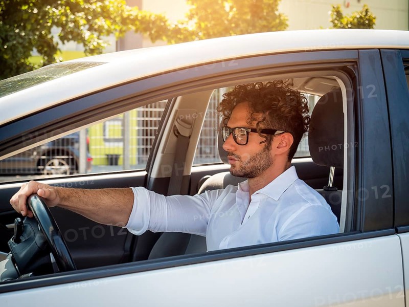 Handsome man sitting in his car, looking straight ahead and driving
