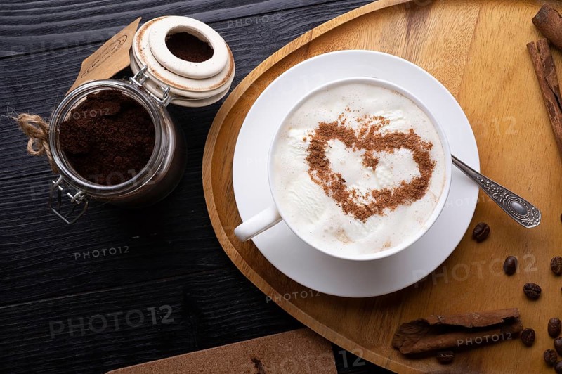 Porcelain cup of coffee with ice cream and cinnamon heart served at black wooden table. life style concept