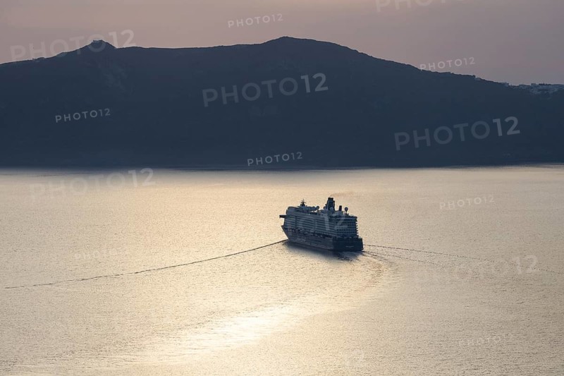 Golden evening light, view from Fira, cruise ship leaving Santorini archipelago, Thirassia island in the background, backlight shot, Santorini island, Cyclades, Greece, Europe