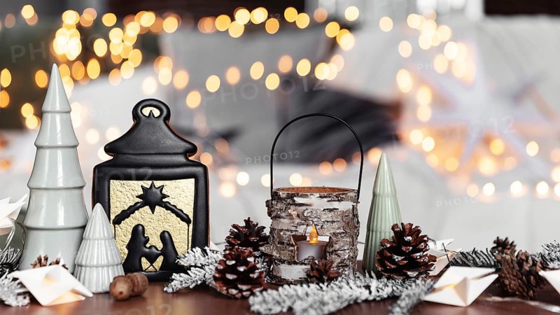 Christmas or New Year composition with various home decorations, different symbolic toys composed and ordered at coffee table with blurred Christmas lights background at sofa white cover. Family time