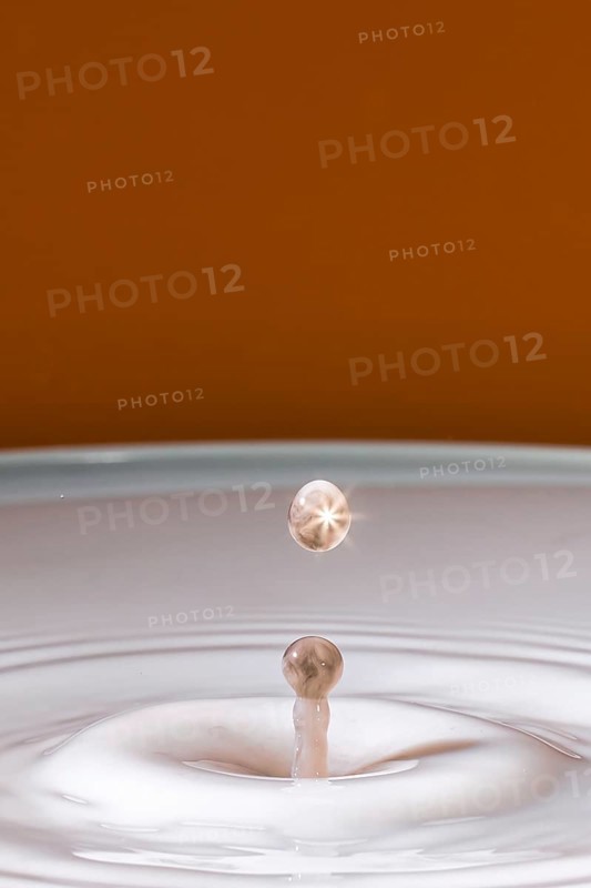 A sparkling drop hits the surface of the milk and creates gentle waves, water droplets, collision, high-speed photography, concept