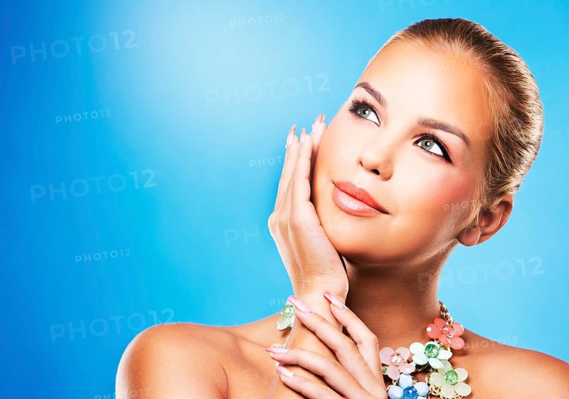 Beautiful woman with dark makeup and pink lipstick posing on blue background wearing flower spring and summer jewellry necklace, Toronto, Canada, North America