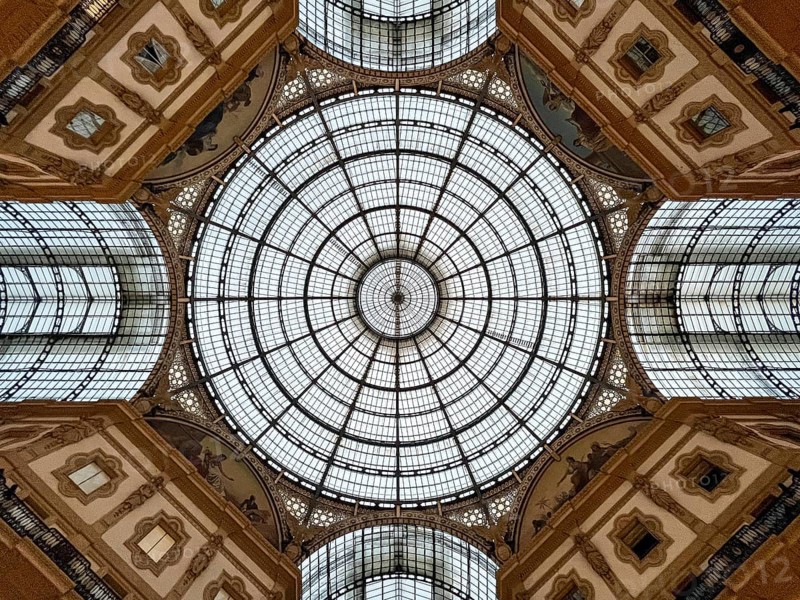 Round stained-glass windows and arches on the ceiling of the Vittorio Emmanuel Gallery. Milan, Italy.