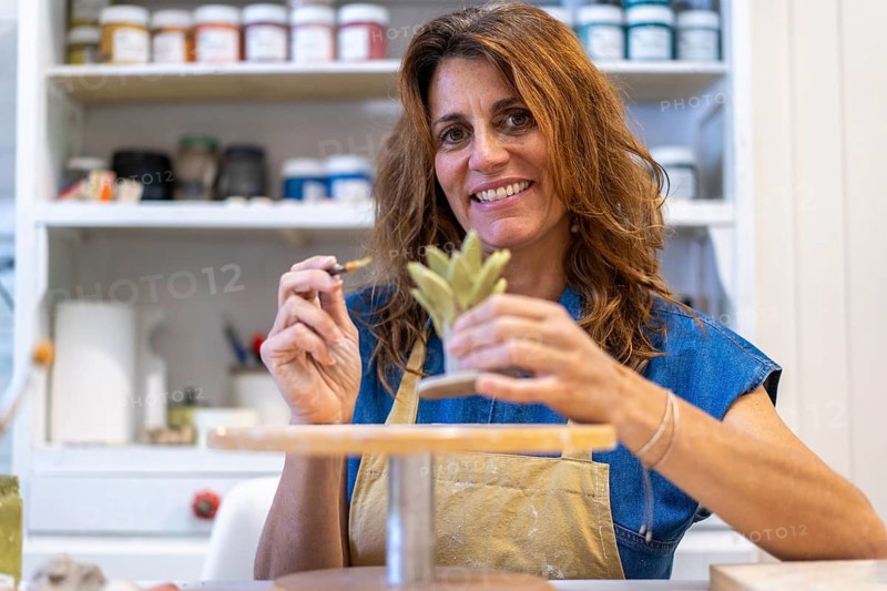 Artist smiling as she perfects her latest pottery piece