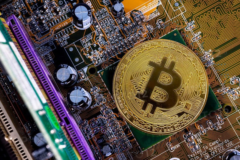 Virtual cryptocurrency money Bitcoin golden coin on a computer printed circuit board PCB. The future of money. Computational equipment. Shot directly from above