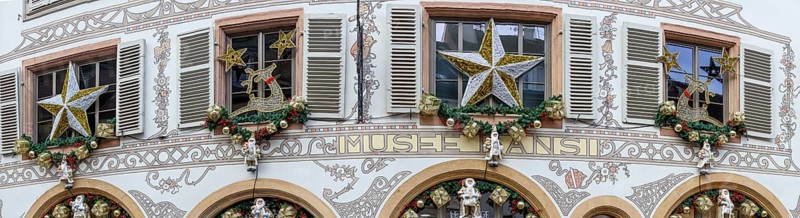 Panoramic photo of a shop front decorated for Christmas with many Father Christmases in golden coats and with golden stars in the Rue des Têtes, Colmar, Alsace, Département Bas-Rhin, France, Europe