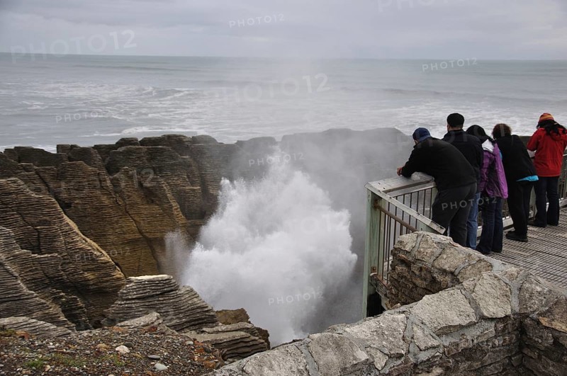 PUNAKAIKI, NEW ZEALAND, MAY 5, 2010: Tourists enjoy the main blowhole in action at the Pancake Rocks, Punakaiki, West Coast, South Island, New Zealand, Oceania