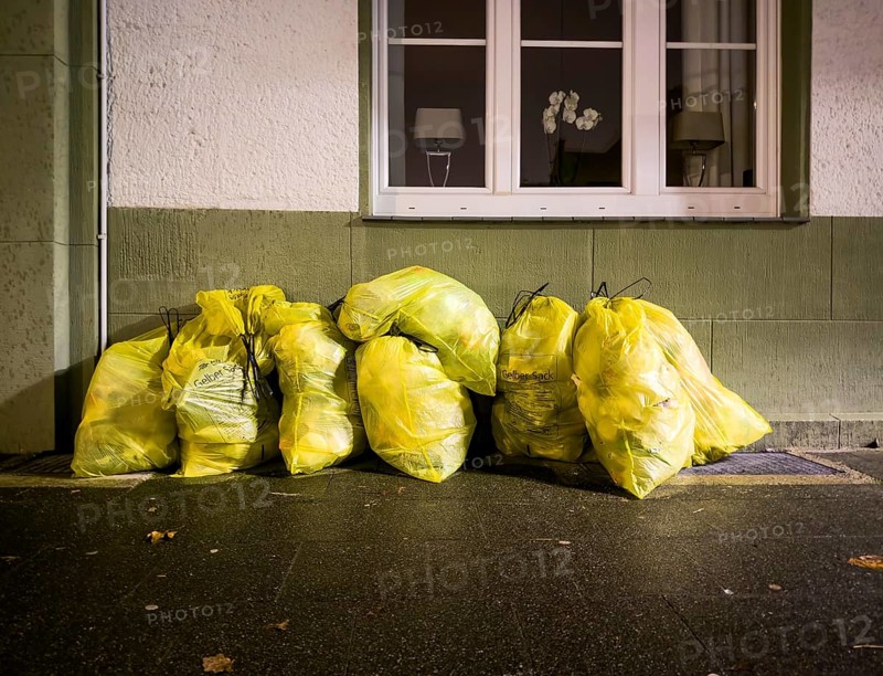 Photo of several bulging yellow rubbish bags that have been put out for collection at the roadside in front of a residential building. The yellow bags are part of the German recycling system and are used for plastic, metal and composite packaging materials, Düsseldorf, Germany, Europe