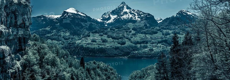 Great panorama over the lake Walensee and its beautiful surroundings, the snowy mountain peaks and huge cliffs, with dark blue colors added. Picture taken near the village Quinten, Switzerland, Europe
