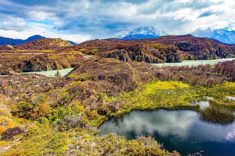 The picturesque River Gray is fed by the glacial melt waters of Lake Gray. Magnificent park Torres del Paine. Chile. The sky and clouds are reflected in the smooth water