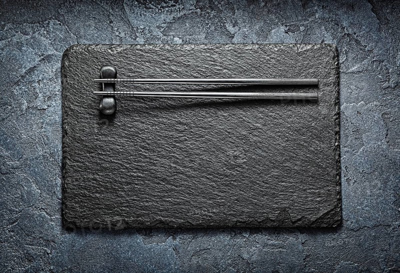 Black Choppingsticks On Rest And Stone Slate Platter
