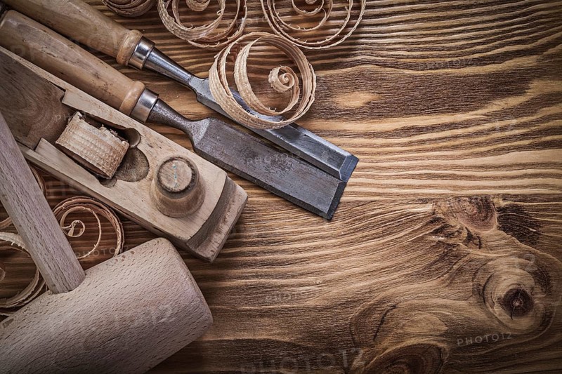 Flat chisels shaving plane curled shavings lump hammer on wooden board construction concept
