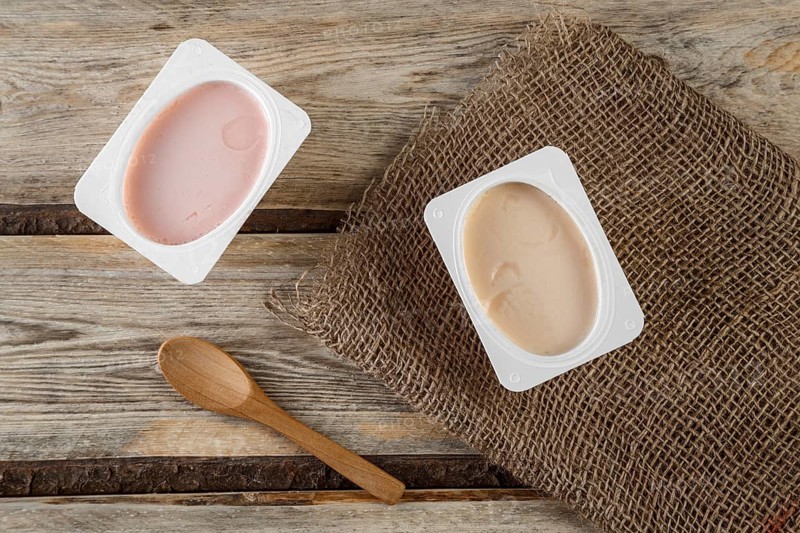 Natural organic yogurt with natural juice on a wooden background with a natural bamboo spoon