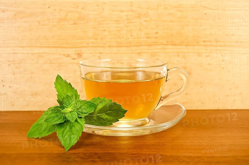 Herbal tea in a glass cup with mint on a background of wooden boards