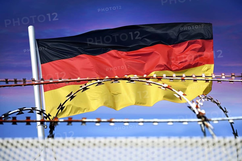 German flag in front of barbed wire, symbolic photo for border controls and rejection at the German national borders, photomontage