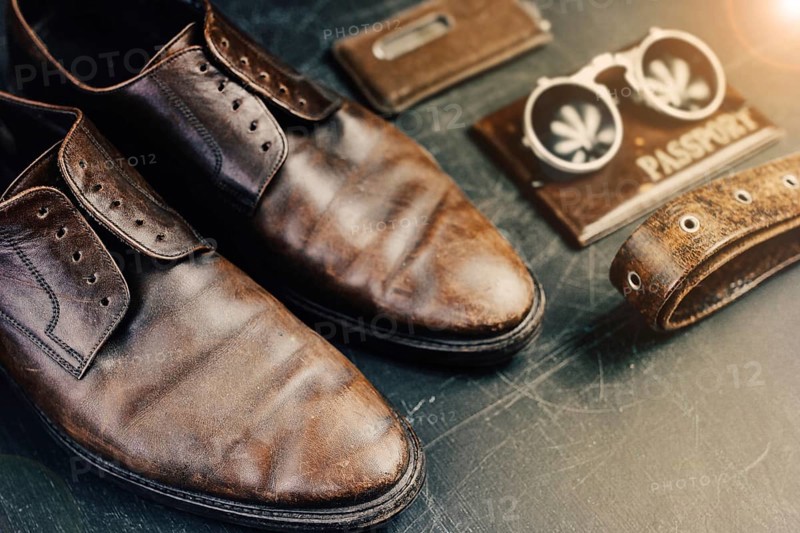 Brown shoes and vintage travel accessories illuminated with a warm lens flare effect