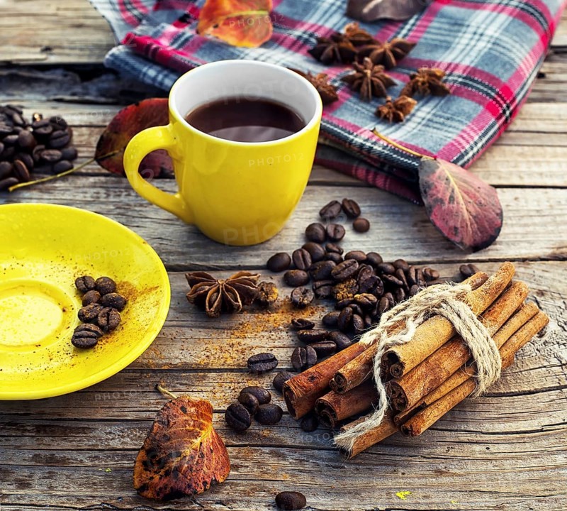 Yellow cup of black coffee on background with autumn leaves