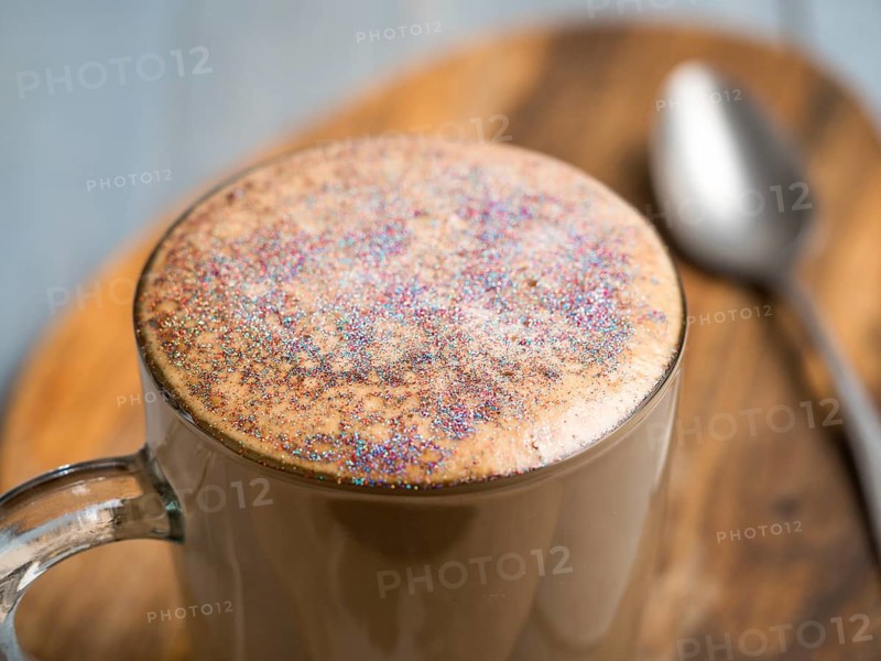 Trendy Coffee with edible glitter. Cup of sparkly coffee or diamond cappuccino on gray table. Copy space for text