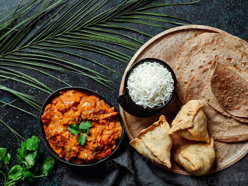 Indian cuisine dishes: tikka masala, rice, samosa, chapati, . Indian food on dark background with copy space. Assortment indian meal top view or flat lay