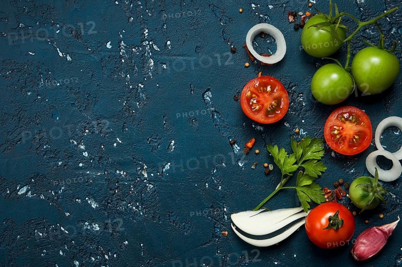 Vegetables background. Fresh vegetables (garlic, tomatoes, onions) on a dark embossed surface. View from above. Copy space