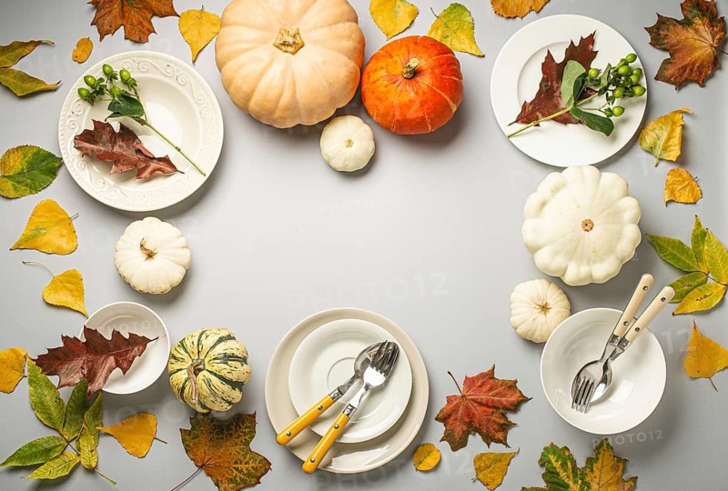 Thanksgiving festive table composition with different colourful pumpkins, autumn leaves, empty plates with cutlery on light grey background table ready for party and celebration. Space for text, food photography, food photography
